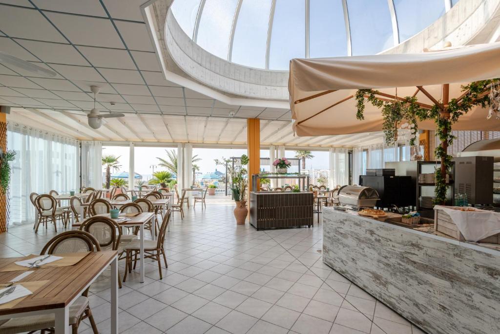 un restaurant avec des tables et des chaises et un plafond de verre dans l'établissement Hotel La Brezza frontemare, à Lido di Jesolo