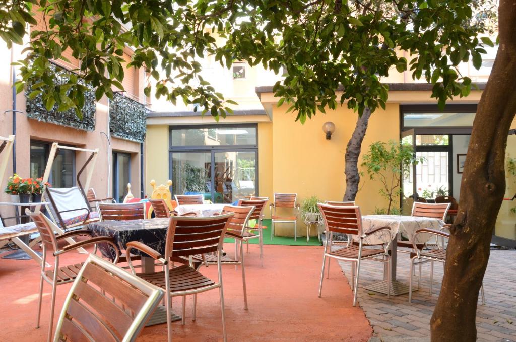 un patio vide avec des tables et des chaises devant un bâtiment dans l'établissement Hotel Villa Lina, à Loano