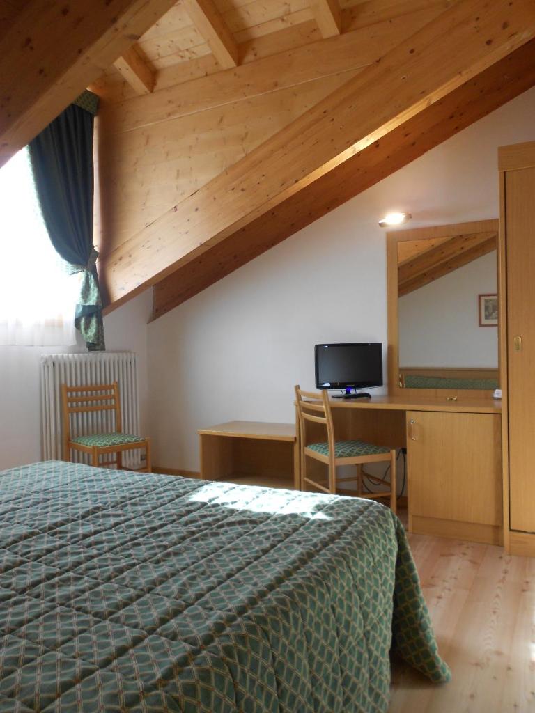 une chambre avec un lit, un bureau et une télévision dans l'établissement Garni Lago Nembia, à San Lorenzo in Banale