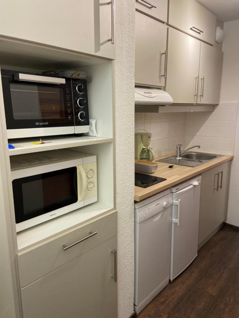 une cuisine avec des armoires blanches et un micro-ondes dans l'établissement Appartement Les Menuires - 4 personnes à 20 m des pistes, aux Menuires