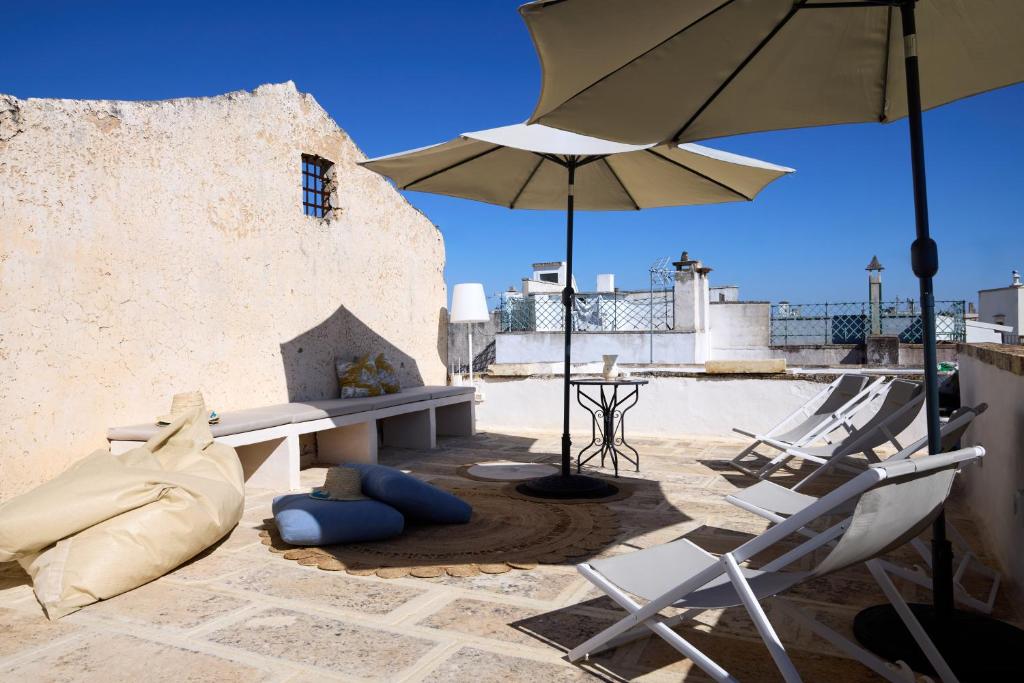 un patio avec une table, des chaises et un parasol dans l'établissement Dimore Arcudi, à Galatina