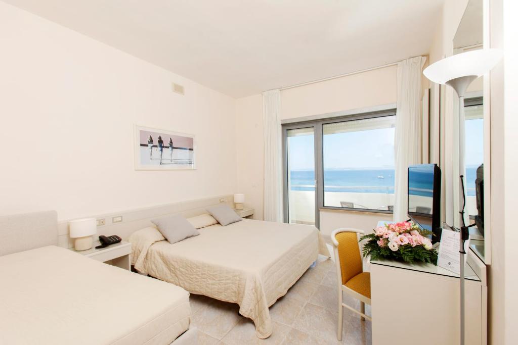 une chambre blanche avec un lit et une télévision dans l'établissement Baia D'Argento, à Porto Santo Stefano