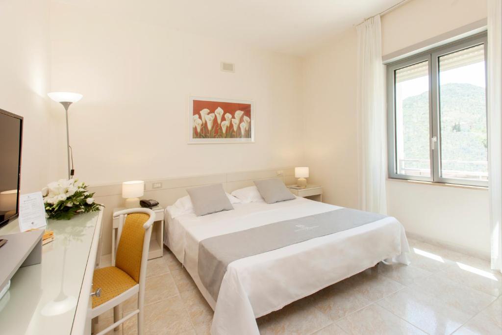 une chambre blanche avec un grand lit et un bureau dans l'établissement Baia D'Argento, à Porto Santo Stefano