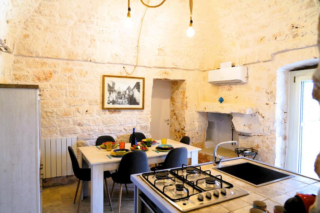 une cuisine avec une cuisinière et une table avec des chaises dans l'établissement Trullo Il Ginepro - FASCINO MEDITERRANEO tra NATURA e STORIA, à Carovigno