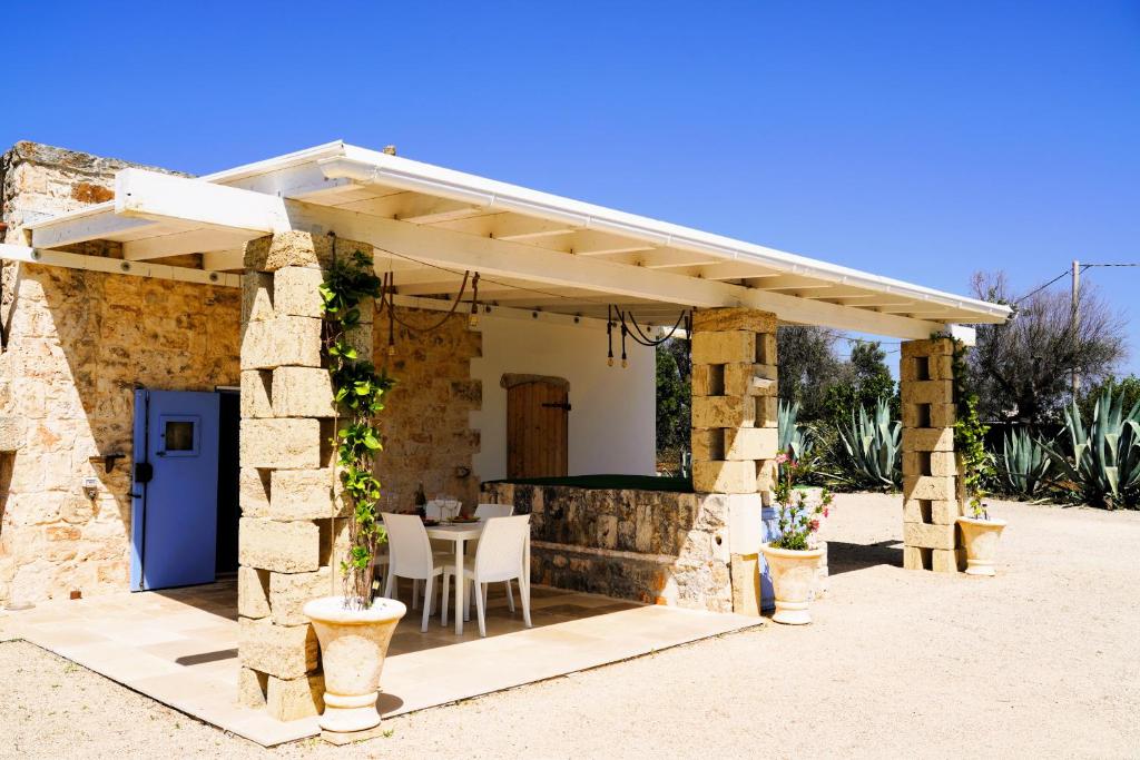 Cette maison en pierre dispose d'une terrasse avec une table. dans l'établissement Trullo Il Ginepro - FASCINO MEDITERRANEO tra NATURA e STORIA, à Carovigno