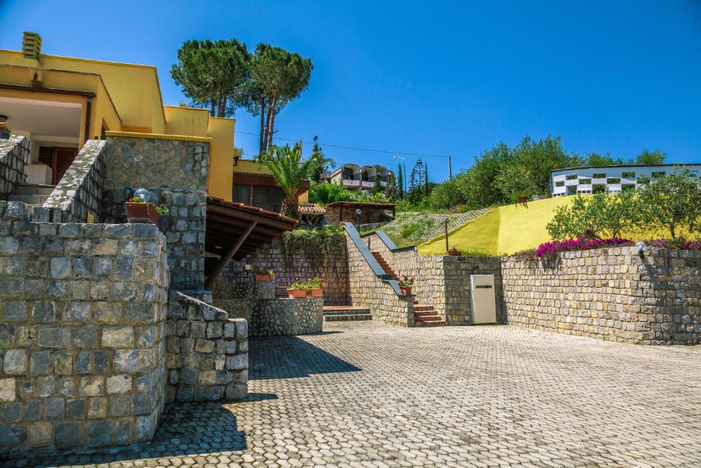 un mur en pierre à côté d'un bâtiment avec une maison dans l'établissement Le Terrazze Palinuro, à Palinuro