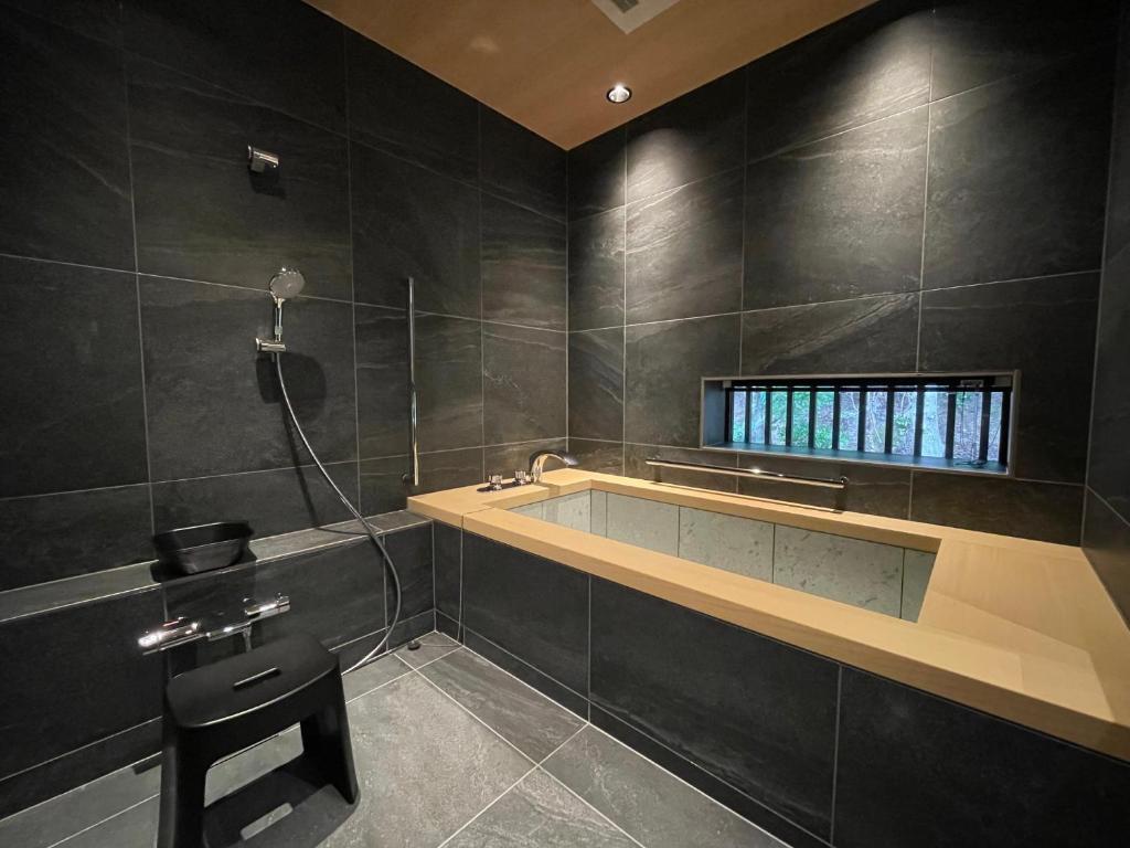 La salle de bains est pourvue d'une baignoire, d'un lavabo et d'un tabouret. dans l'établissement Kikunoya, à Miyajima