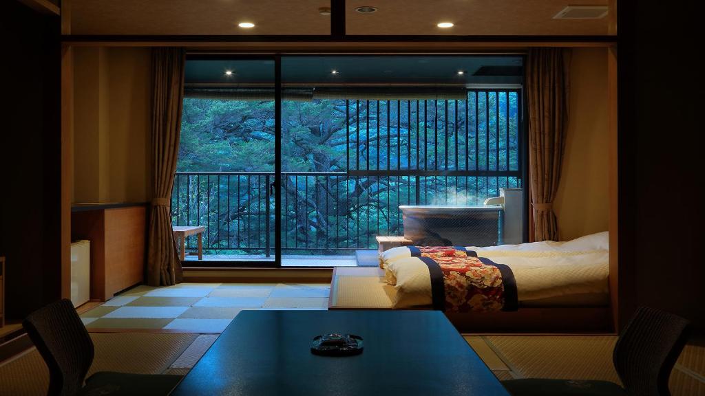 Cette chambre comprend un lit et une grande fenêtre. dans l'établissement Tsuganoki, à Nikkō