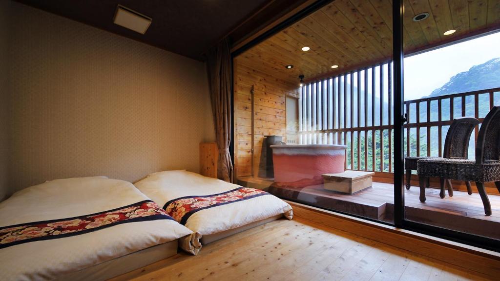 une chambre avec un lit et une grande fenêtre dans l'établissement Tsuganoki, à Nikkō 37 autres photos