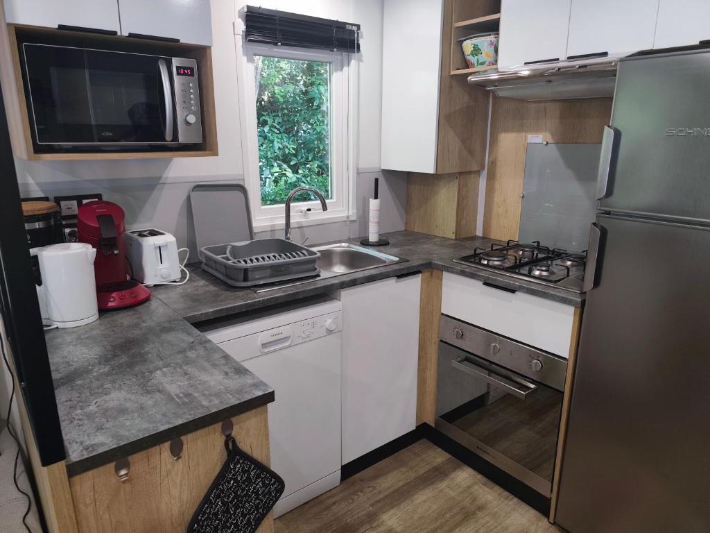 une petite cuisine avec un évier et un réfrigérateur dans l'établissement Jolie Mobil Home climatisé 58, à Saint-Jean-de-Monts