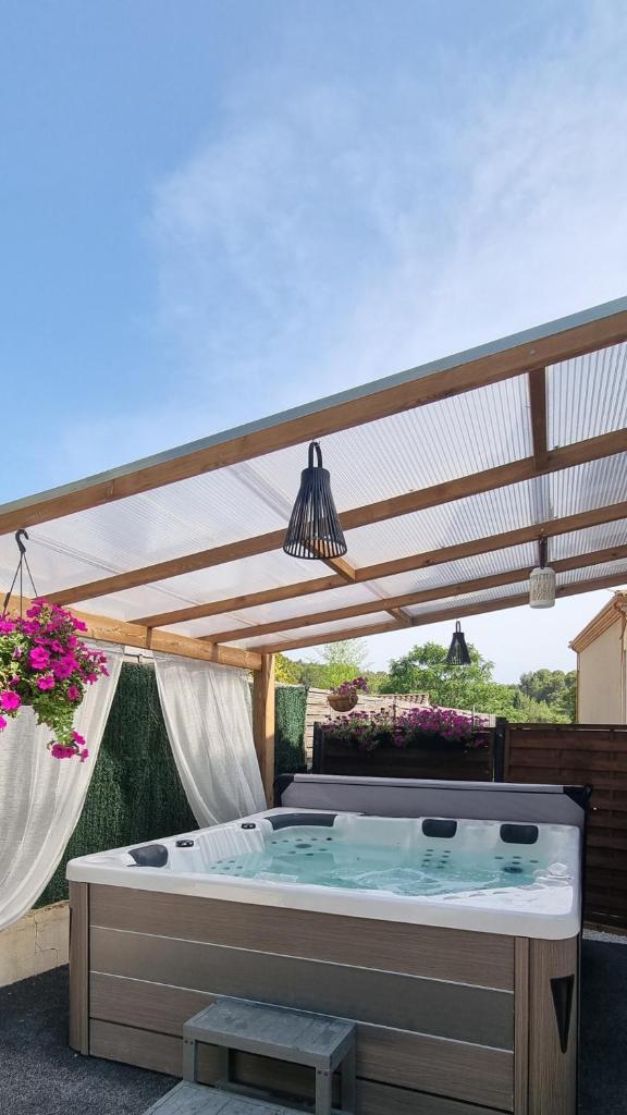 Un bain à remous est installé sous une pergola en bois. dans l'établissement Le Gîte de la Fontaine - Aumes, à Aumes