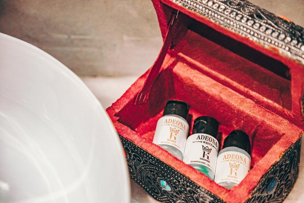 trois bouteilles de vin dans une boîte rouge à côté d'une assiette dans l'établissement Riad Tislite & SPA, à Marrakech