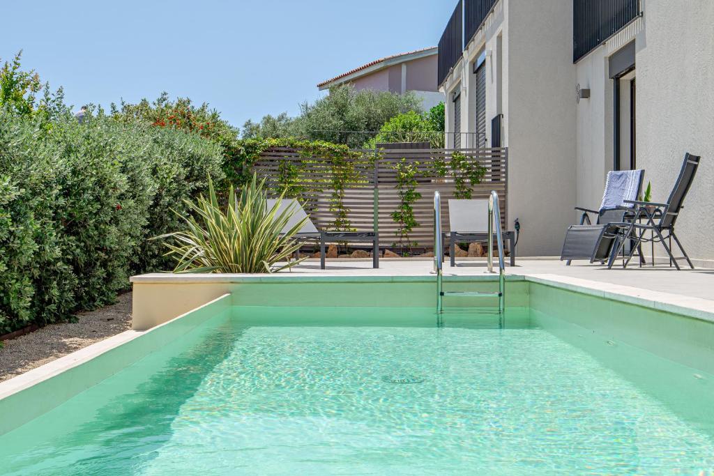 - une piscine avec une table et des chaises à côté d'une maison dans l'établissement Mirtina Home, à Golfo Aranci