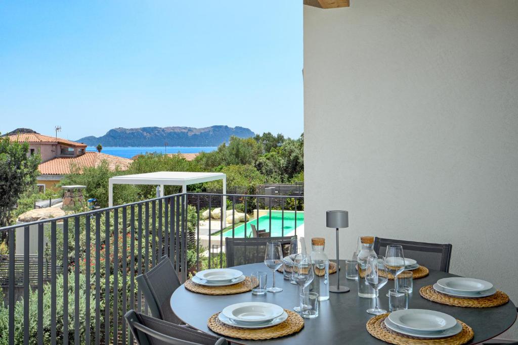 une table avec des verres et des assiettes sur un balcon dans l'établissement Mirtina Home, à Golfo Aranci