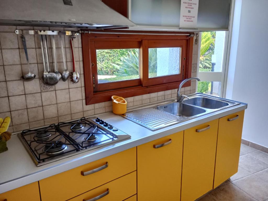 une cuisine avec un évier, une cuisinière et une fenêtre dans l'établissement Villa Terrauzza, à Syracuse