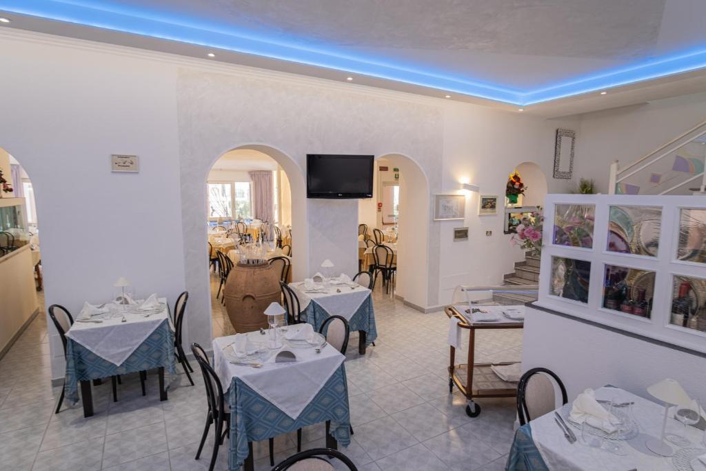 un restaurant avec des tables et des chaises et une télévision au mur dans l'établissement Hotel Ristorante Borgo La Tana, à Maratea