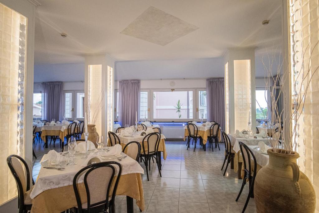 une salle à manger avec tables, chaises et fenêtres dans l'établissement Hotel Ristorante Borgo La Tana, à Maratea