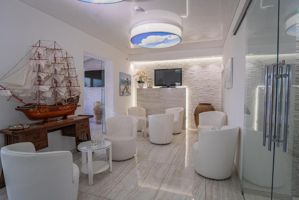 une pièce avec des chaises blanches et un bateau au mur dans l'établissement Hotel Ristorante Borgo La Tana, à Maratea