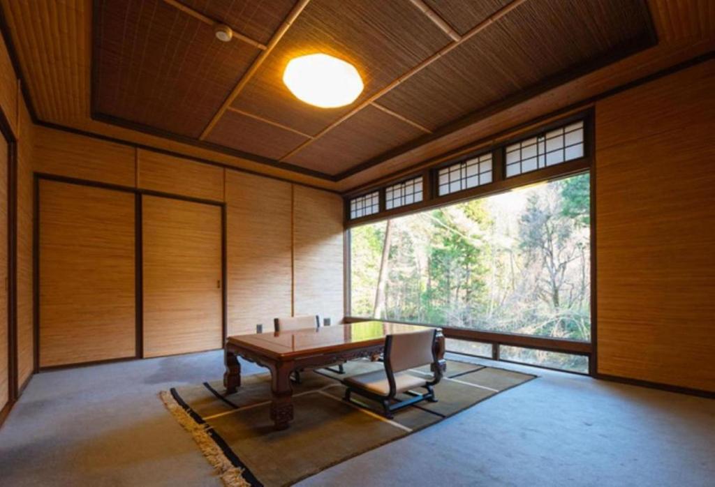une pièce avec une table et une grande fenêtre dans l'établissement Wanosato, à Takayama