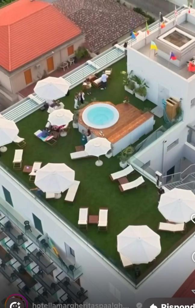 un modèle d'arrière-cour avec une piscine, des tables et des parasols dans l'établissement Hotel La Margherita & SPA, à Alghero