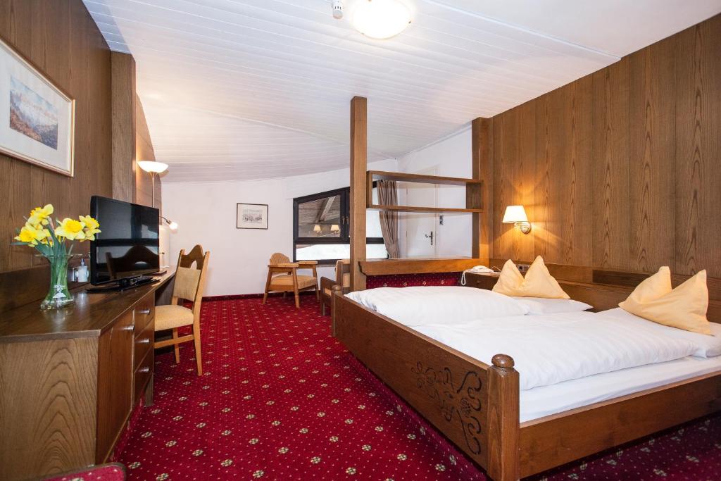 une chambre d'hôtel avec un grand lit et une télévision dans l'établissement Hotel Am Wolfgrubenersee, à Soprabolzano 47 autres photos