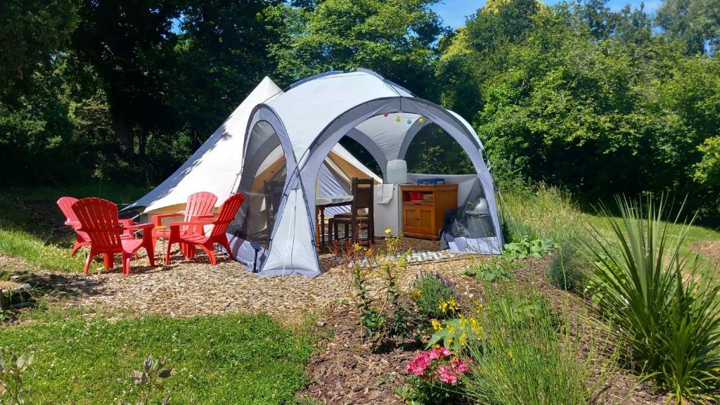 une tente avec des chaises et une table dans une cour dans l'établissement Tente insolite en pleine nature, à Tréduder