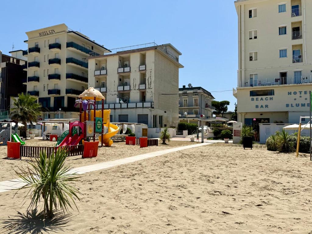 une aire de jeux sur la plage devant un immeuble dans l'établissement Residence Algarve, à Rimini