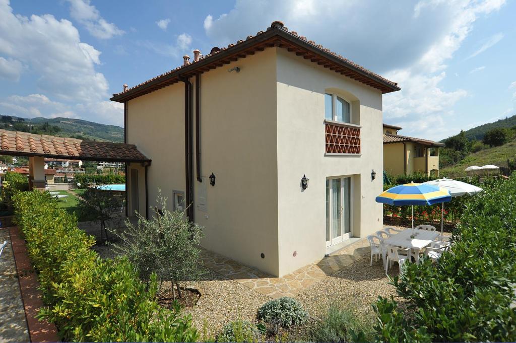 une maison avec un parasol, une table et des chaises dans l'établissement Casa Rosa, à Greve in Chianti
