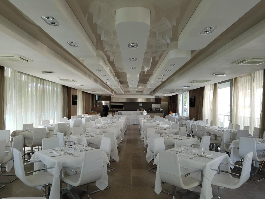 une salle de banquet avec des tables blanches et des chaises blanches dans l'établissement Hotel Sorriso, à Milano Marittima