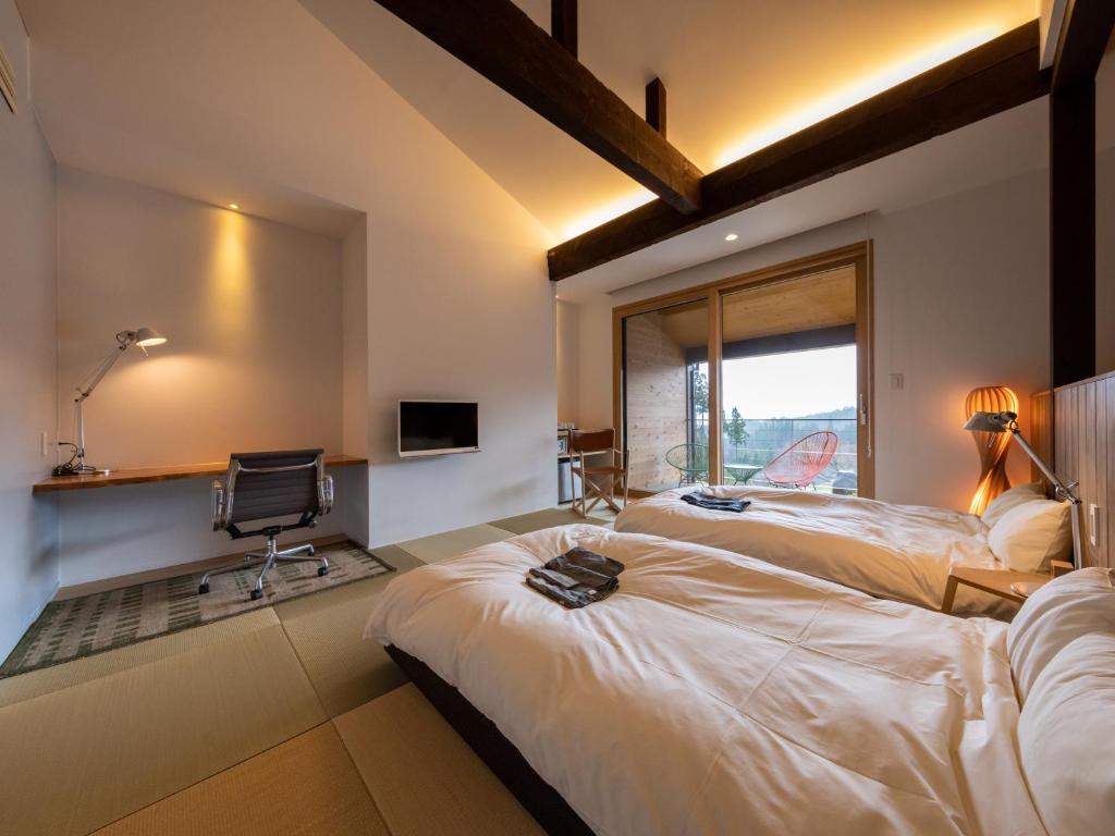 une chambre d'hôtel avec deux lits et une fenêtre dans l'établissement Satoyama Jujo, à Minami Uonuma