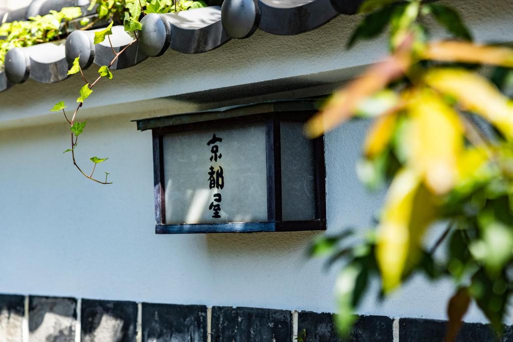 une lanterne sur le côté d'un bâtiment avec une écriture dessus dans l'établissement Kyotoya, à Takeo
