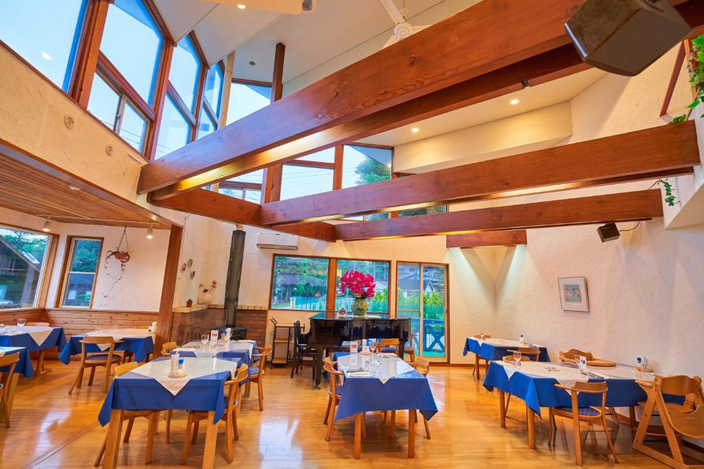 un restaurant avec des tables, des chaises et un piano dans l'établissement Manor House, à Yamanakako