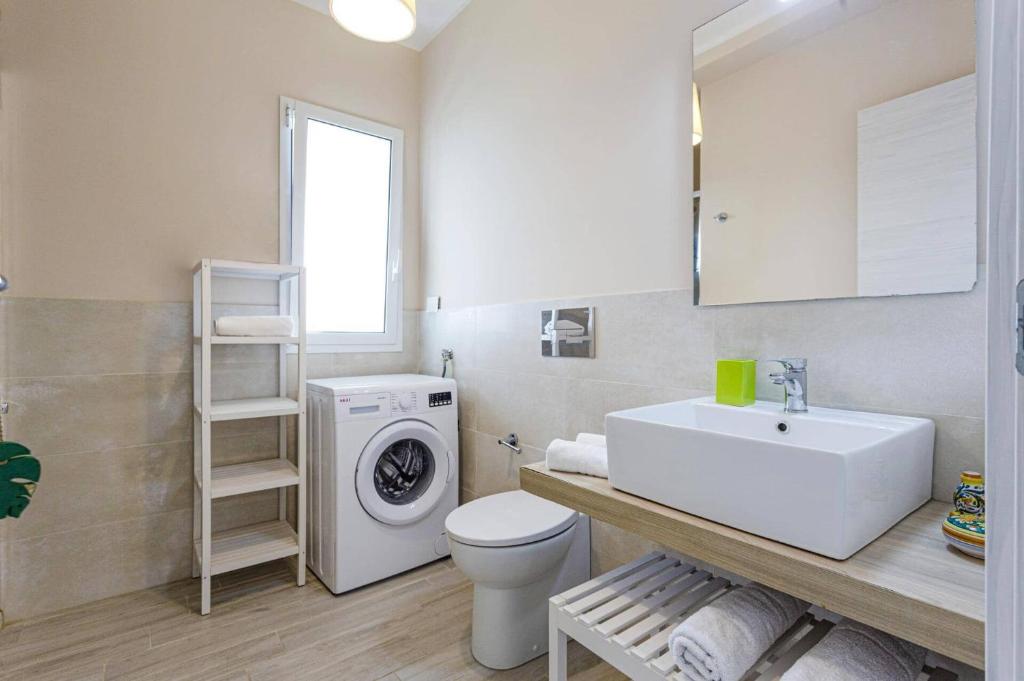 une salle de bain avec un lavabo et une machine à laver dans l'établissement Villa Luce by Villa Plus, à Santa Maria Del Focallo