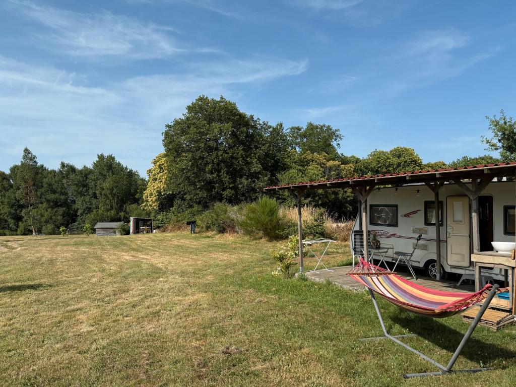 un camping avec une tente, une table et des hamacs dans l'établissement Caravanne 4 Pers Vue Sur L'étang, à Champsac 13 autres photos
