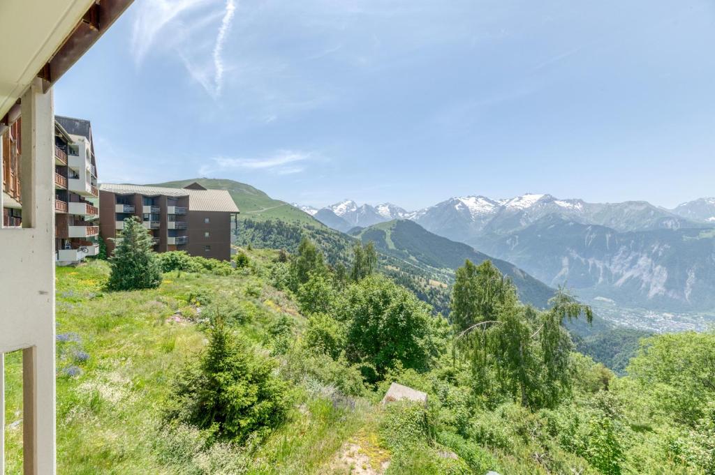 un bâtiment sur une colline avec des montagnes en arrière-plan dans l'établissement Studio Montagnard Vue Splendide, à L'Alpe-d'Huez