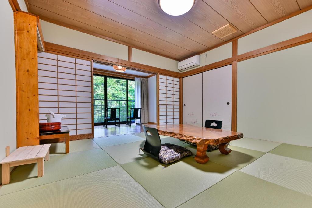 Cette chambre comprend une table en bois et une chaise. dans l'établissement 山川温泉 小杉庵, à Oguni