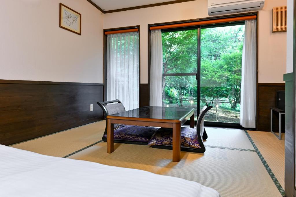 - une chambre avec une table, un lit et une fenêtre dans l'établissement 山川温泉 小杉庵, à Oguni