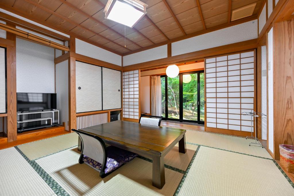 - un salon avec une table en bois et une télévision dans l'établissement 山川温泉 小杉庵, à Oguni