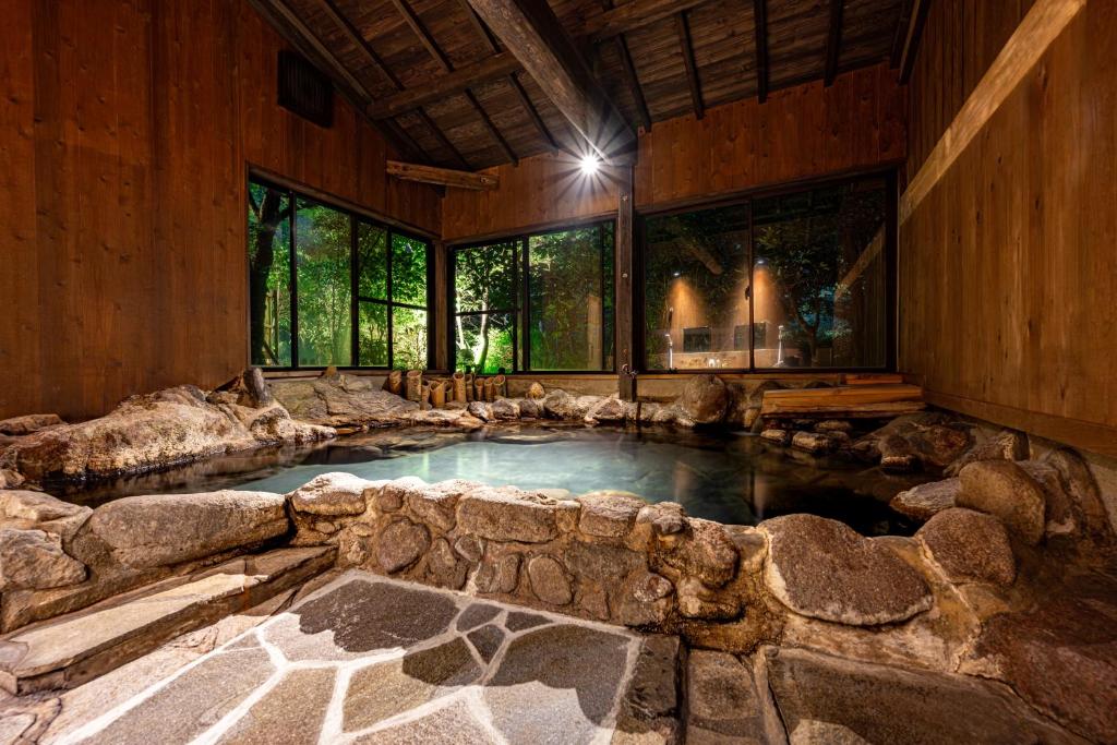 une grande piscine intérieure dans une pièce avec un mur en pierre dans l'établissement 山川温泉 小杉庵, à Oguni