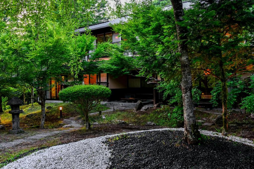 une maison entourée d'arbres et d'une allée de gravier dans l'établissement 山川温泉 小杉庵, à Oguni