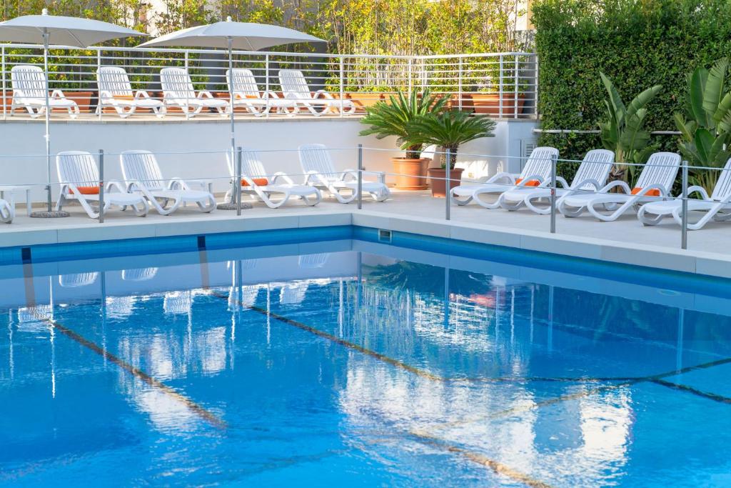 - une piscine avec des chaises blanches et de l'eau bleue dans l'établissement Hotel Palace Magnolia SPA, à Tortoreto Lido