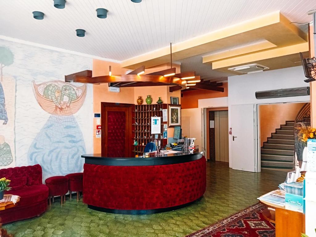 - un hall avec un bar et des chaises rouges dans l'établissement Hotel Galles, à Lido di Jesolo