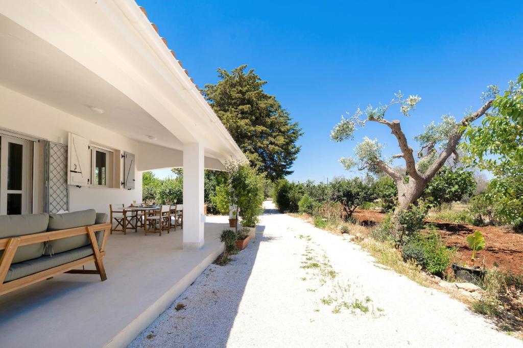 une terrasse couverte d'une maison avec un banc et un arbre dans l'établissement Meraki house con piscina privata, à San Michele Salentino