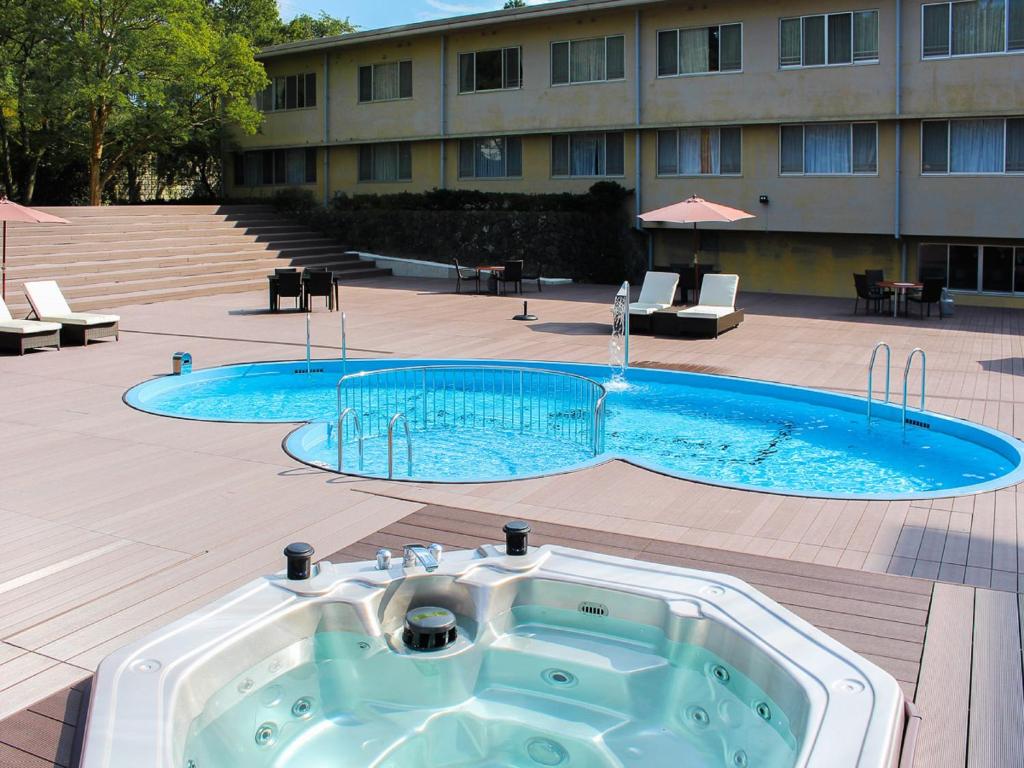 un bain à remous en face d'un grand bâtiment dans l'établissement LiVEMAX RESORT Kaga Yamashiro, à Kaga