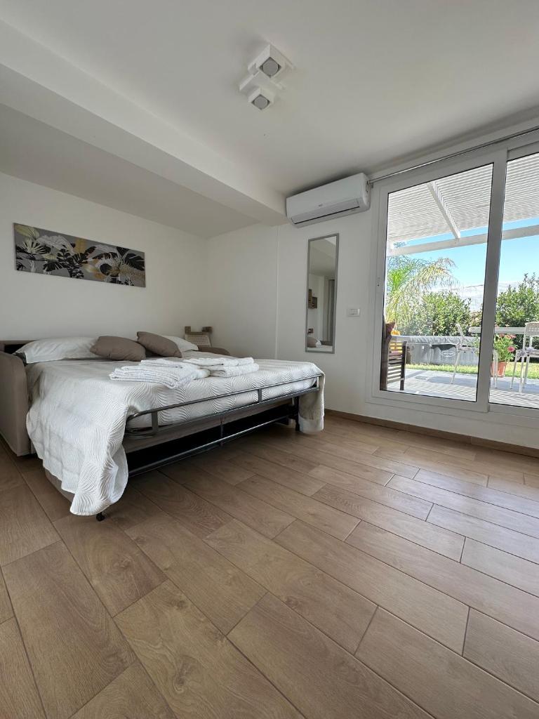 une chambre blanche avec un lit et une grande fenêtre dans l'établissement Villa Matilde, à Marina di Ragusa