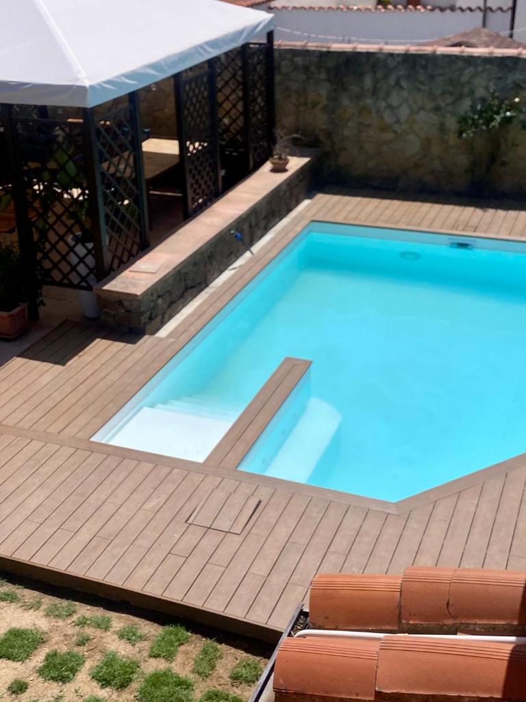 une piscine avec une terrasse en bois et une visière de piscine dans l'établissement VIlla Sunlight Sardegna, à Santa Luria