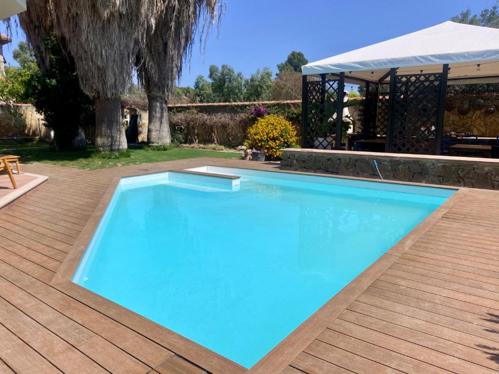 une grande piscine bleue sur une terrasse en bois dans l'établissement VIlla Sunlight Sardegna, à Santa Luria