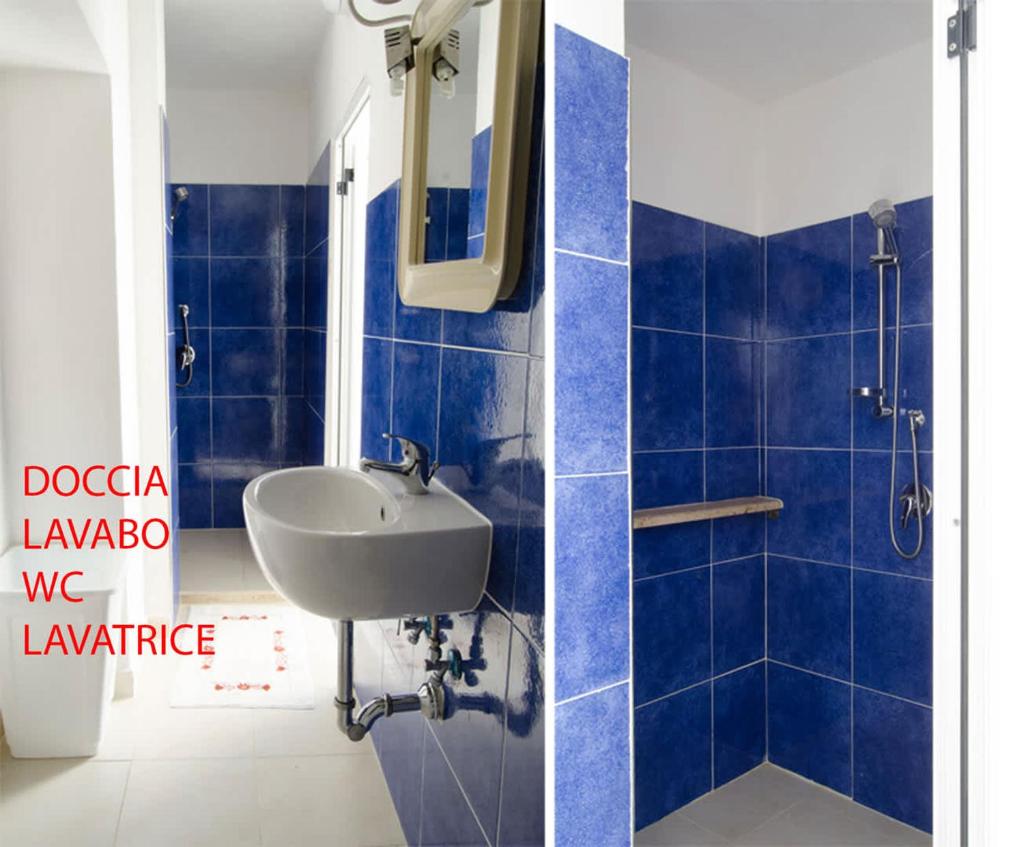 La salle de bains est pourvue de carrelage bleu, d'un lavabo et d'un miroir. dans l'établissement Villa Maria con Piscina nel Boomerang Village a Torre Colimena, à Torre Colimena