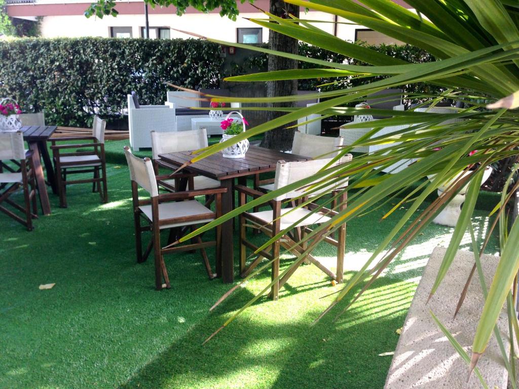une table et des chaises en bois dans une cour avec de l'herbe verte dans l'établissement Hotel Jole, à San Mauro a Mare