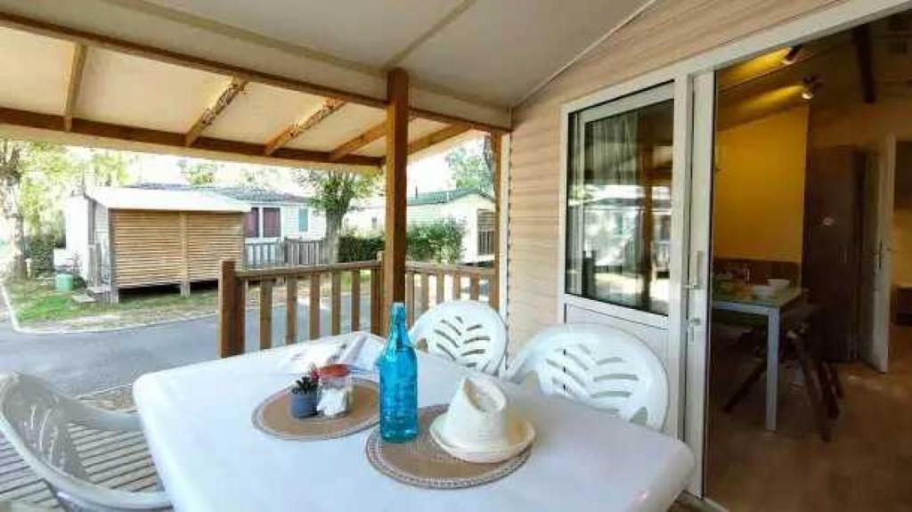 - une table et des chaises blanches sur une terrasse couverte dans l'établissement Appartement 4 étoiles - Parc aquatique - ccaa0ai, à Bormes-les-Mimosas